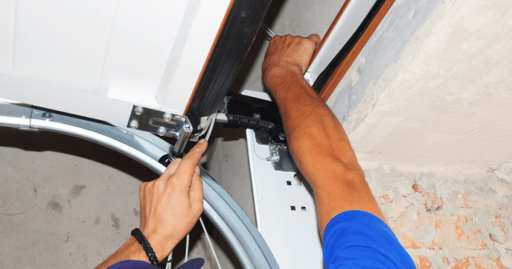 Technician adjusting garage door cable system.